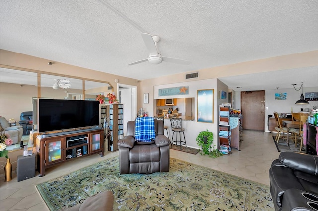 living area with visible vents, a textured ceiling, ceiling fan, and tile patterned flooring