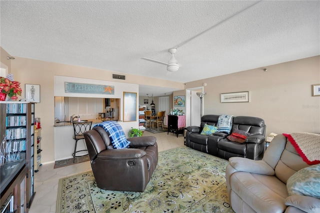 living area with light tile patterned flooring, visible vents, and a textured ceiling