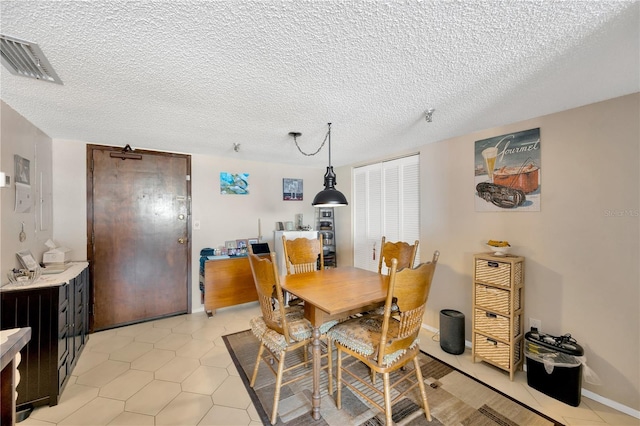 dining space with light tile patterned flooring, baseboards, visible vents, and a textured ceiling