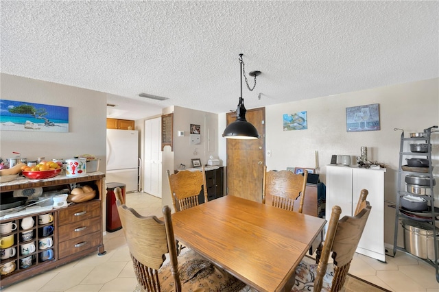 dining room with light tile patterned floors, visible vents, and a textured ceiling