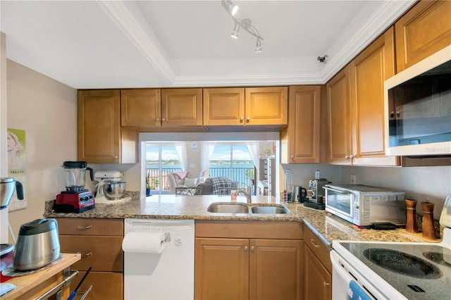 kitchen featuring a sink, white appliances, brown cabinets, and light stone countertops