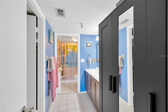 bathroom with vanity, tile patterned floors, visible vents, and a textured ceiling