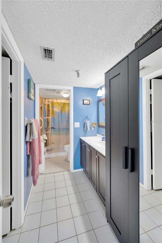 bathroom featuring tile patterned floors, visible vents, a textured ceiling, and toilet