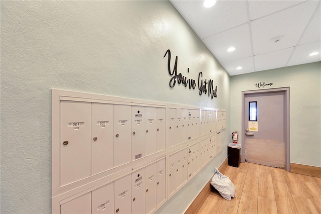 hallway with mail area, recessed lighting, baseboards, light wood-style floors, and a paneled ceiling