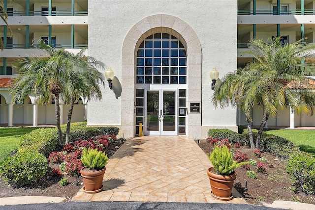 doorway to property with french doors, fence, and stucco siding