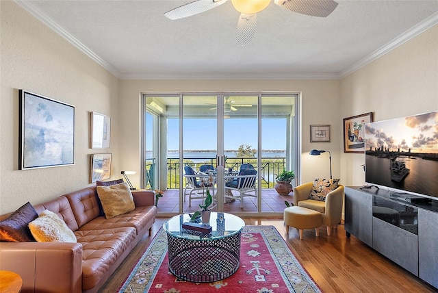 living area featuring a ceiling fan, a textured ceiling, wood finished floors, crown molding, and a textured wall