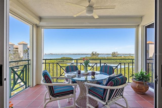 sunroom / solarium with a ceiling fan, a water view, and a wealth of natural light