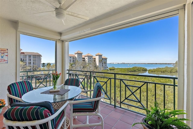 balcony with ceiling fan and a water view