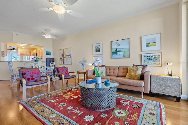 living area with baseboards, crown molding, and light wood finished floors