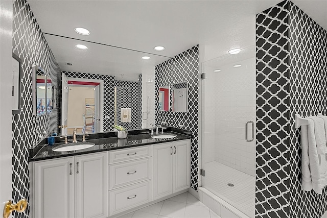 bathroom featuring tile patterned floors, a stall shower, double vanity, and a sink