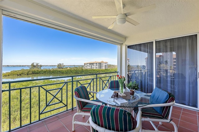 balcony featuring a water view and ceiling fan