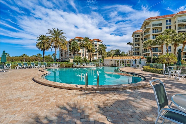 community pool with a patio area and fence