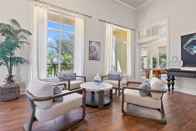 sitting room with crown molding, a high ceiling, baseboards, and wood finished floors