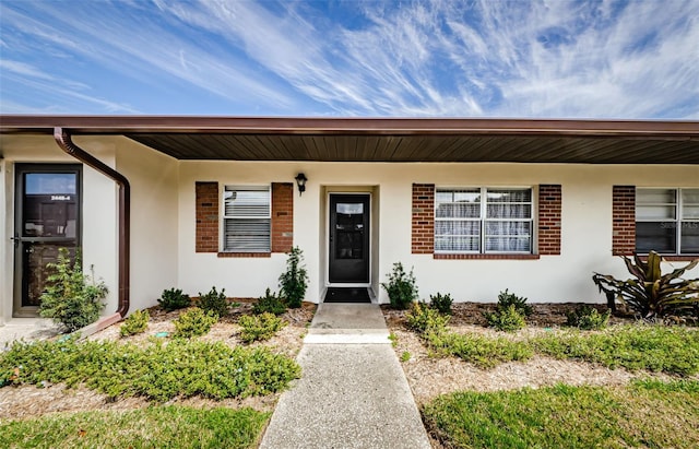 entrance to property featuring brick siding and stucco siding