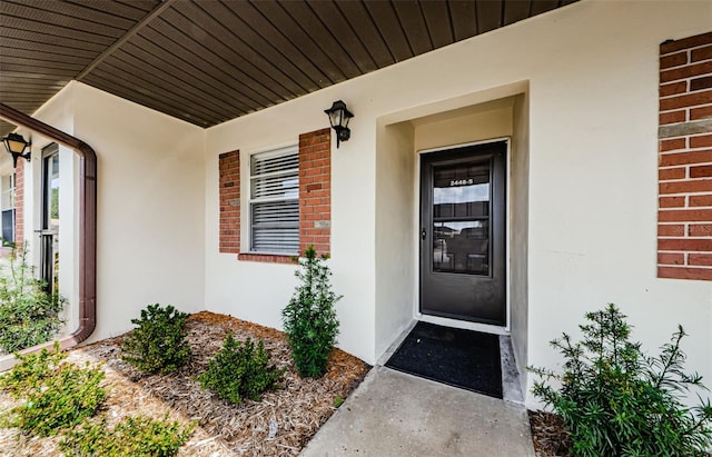 doorway to property with stucco siding and brick siding