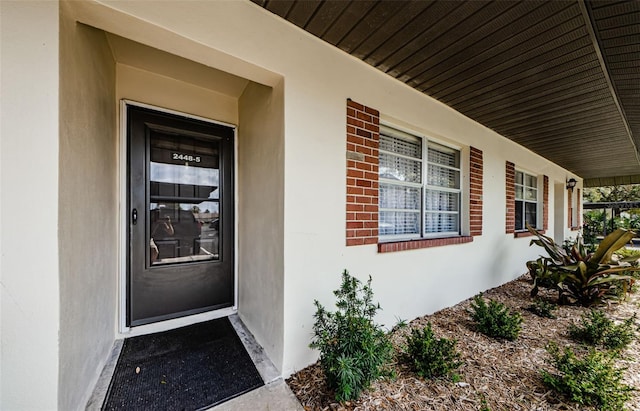 view of exterior entry featuring covered porch and stucco siding