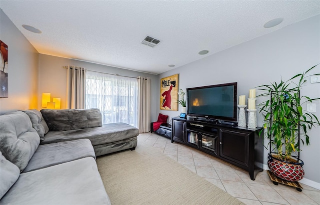 living area featuring light tile patterned flooring, visible vents, a textured ceiling, and baseboards