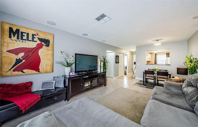 living room with light tile patterned floors, visible vents, a textured ceiling, and baseboards