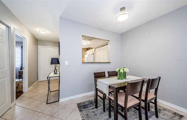 dining space featuring light tile patterned floors, visible vents, baseboards, and a textured ceiling