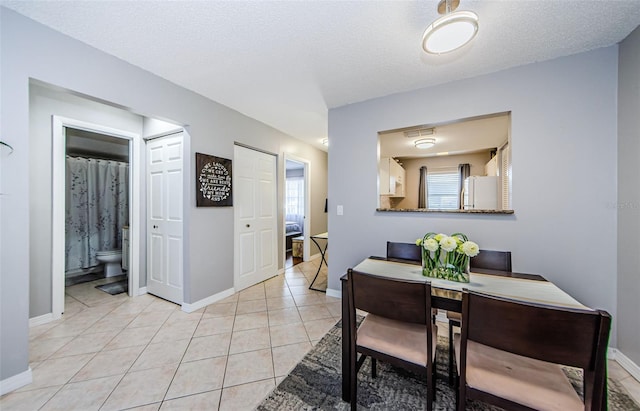 dining space featuring visible vents, baseboards, a textured ceiling, and light tile patterned flooring