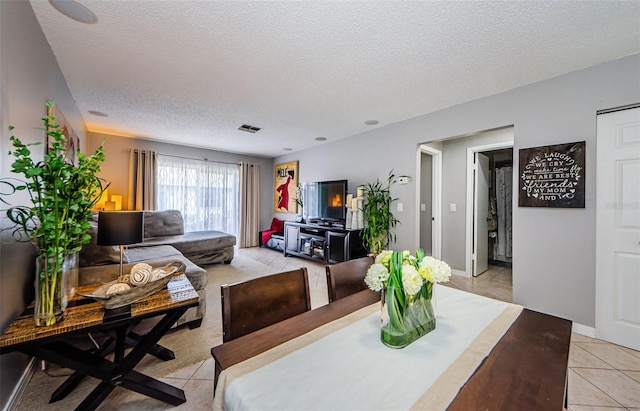 dining area with visible vents, baseboards, a textured ceiling, and light tile patterned flooring