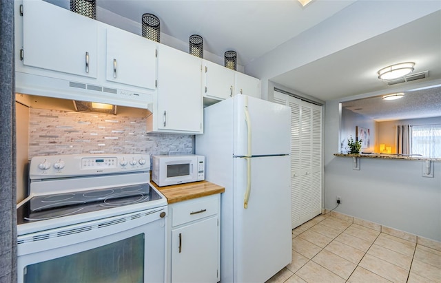 kitchen with visible vents, under cabinet range hood, white appliances, white cabinets, and light tile patterned floors