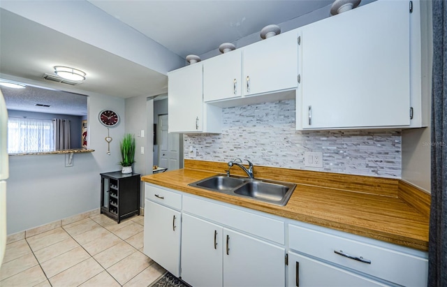 kitchen featuring visible vents, a sink, white cabinetry, light tile patterned floors, and decorative backsplash