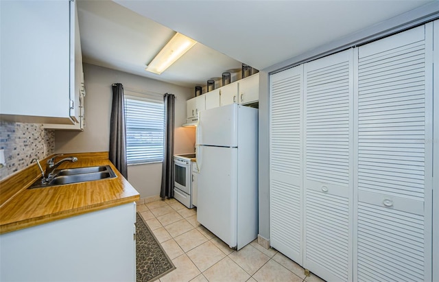 kitchen with light tile patterned floors, decorative backsplash, white cabinets, white appliances, and a sink