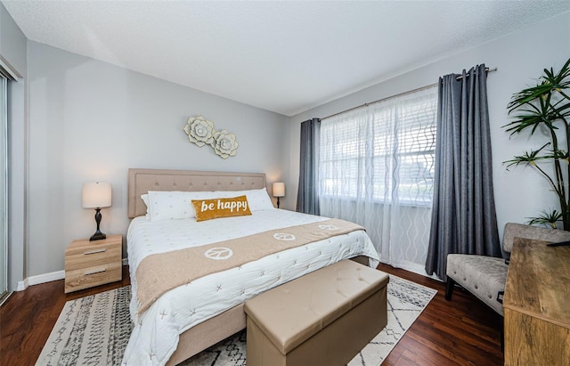 bedroom featuring a textured ceiling, baseboards, and wood finished floors