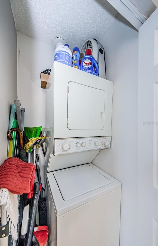 clothes washing area with a textured ceiling and stacked washing maching and dryer