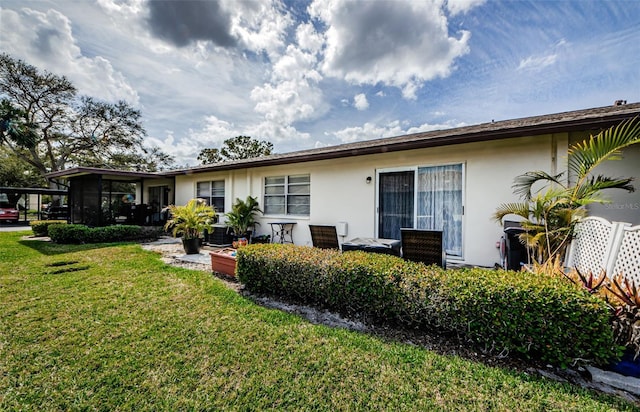 back of house featuring stucco siding and a yard