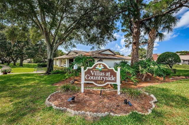 community / neighborhood sign with a lawn and fence