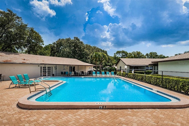 pool with a patio area and fence