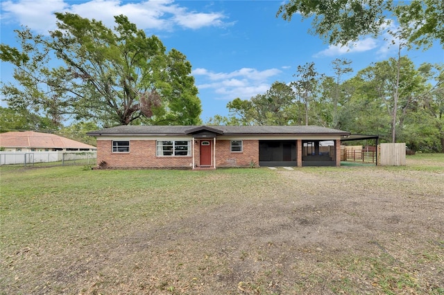 view of front of property with driveway, fence, a front yard, a carport, and brick siding