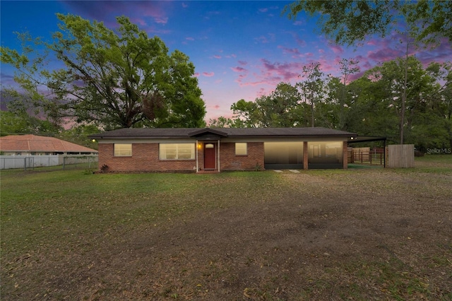 view of front of house featuring fence, driveway, a carport, a lawn, and brick siding