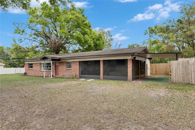 back of house with a lawn, fence, an attached garage, a sunroom, and brick siding