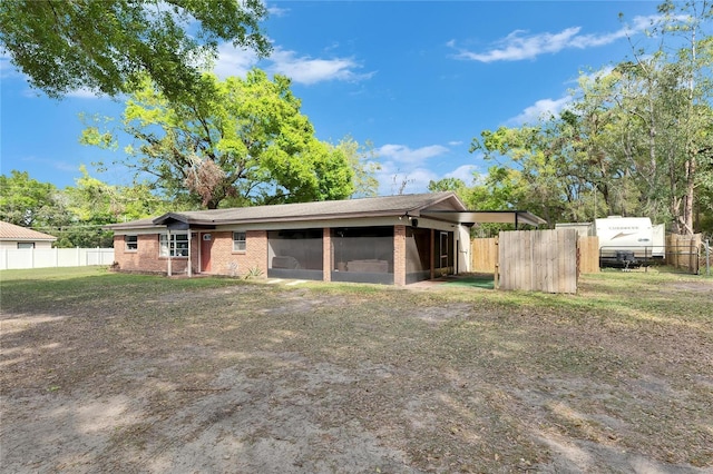 exterior space featuring brick siding, a front lawn, fence, a carport, and driveway