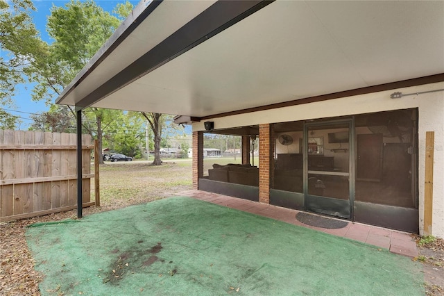 view of patio featuring fence and a sunroom