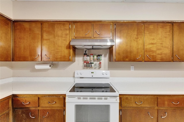 kitchen featuring white electric range oven, light countertops, brown cabinets, and under cabinet range hood