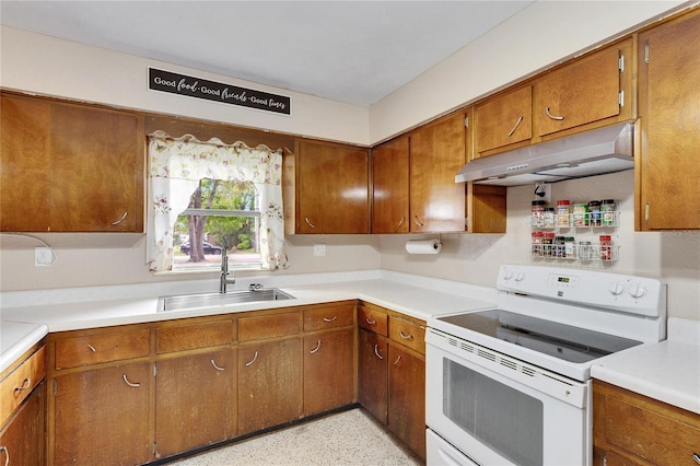 kitchen with electric range, under cabinet range hood, a sink, brown cabinetry, and light countertops