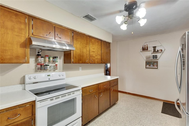 kitchen with under cabinet range hood, brown cabinets, freestanding refrigerator, and white electric stove