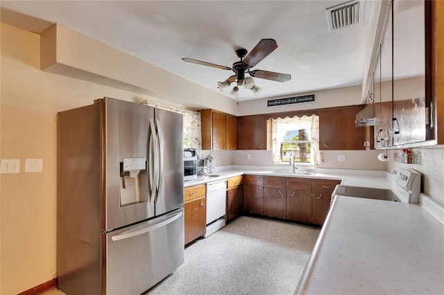 kitchen with visible vents, under cabinet range hood, light countertops, stainless steel appliances, and a sink