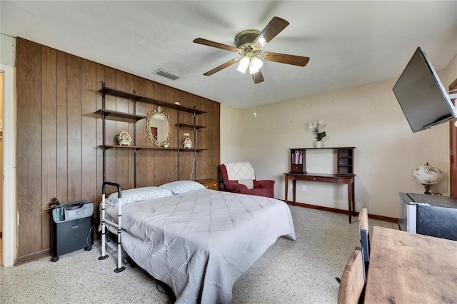 bedroom featuring visible vents, ceiling fan, baseboards, and wooden walls