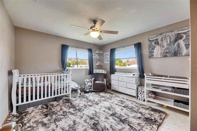 bedroom featuring a nursery area and a ceiling fan