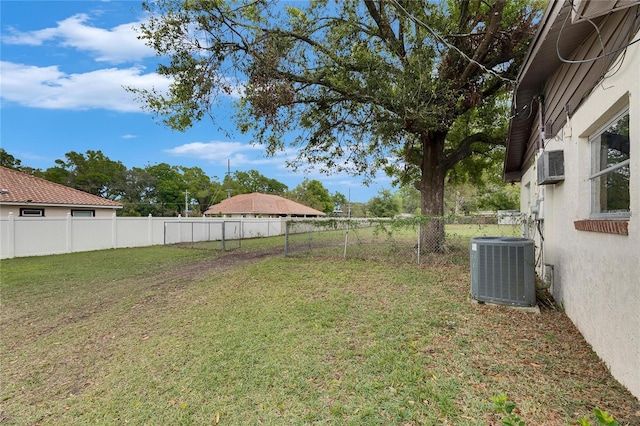 view of yard with cooling unit, a fenced backyard, and a wall unit AC