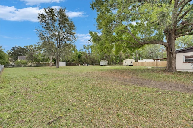 view of yard featuring an outbuilding, a storage unit, and fence