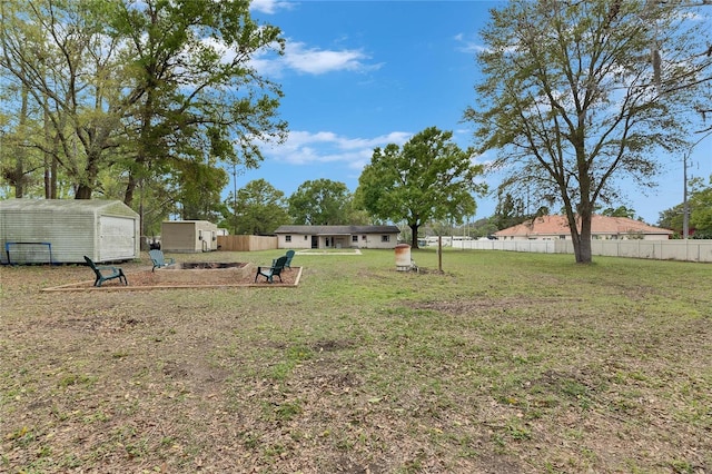 view of yard featuring a storage unit, an outdoor structure, and fence