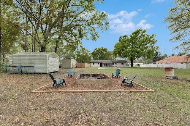 view of yard featuring an outbuilding, a shed, a fire pit, and fence