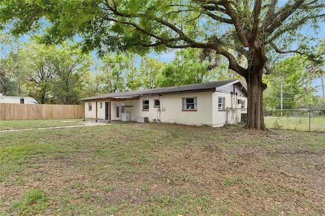 view of front of property featuring stucco siding, a fenced backyard, and a front lawn