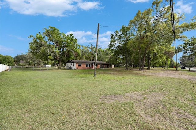 view of yard with dirt driveway and fence